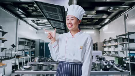 아시아 여인 요리사 는 미소 짓고 전문적 인 부 에서  을 가리키고 있다