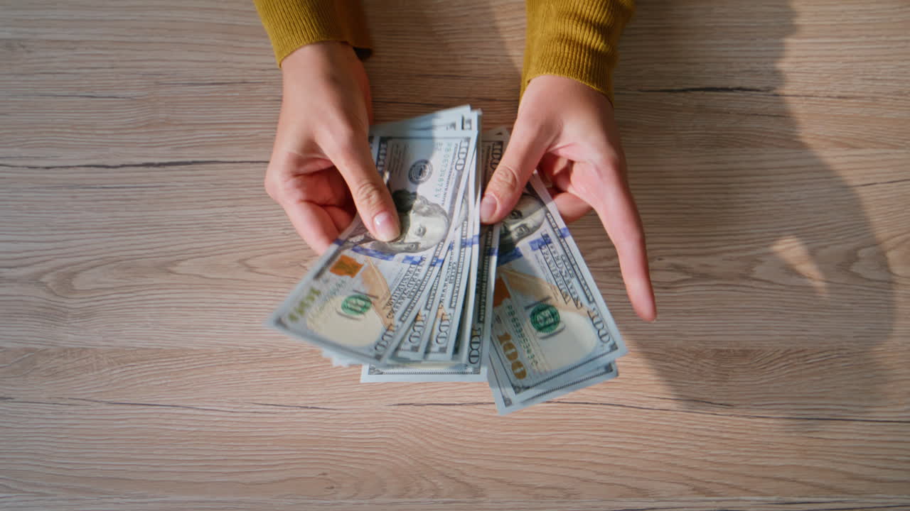 Hands counting US dollars at wooden desk closeup top view. Unknown woman money