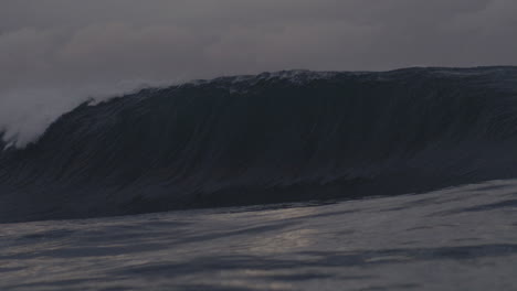 steep wave rises up into wall of water crashing making a deep barrel