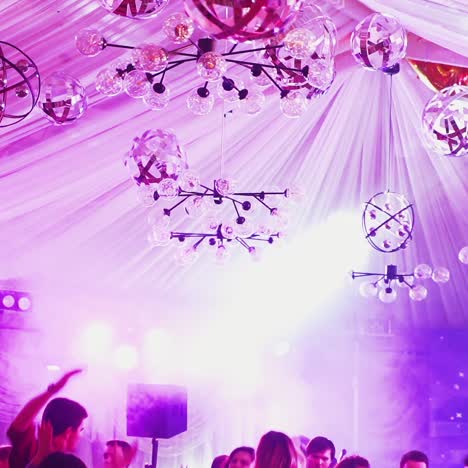 beautiful ceiling with colored lights at nightclub. different sized looped stage lamps on the ceiling and lasers canons shimmering over people in the disco hall.
