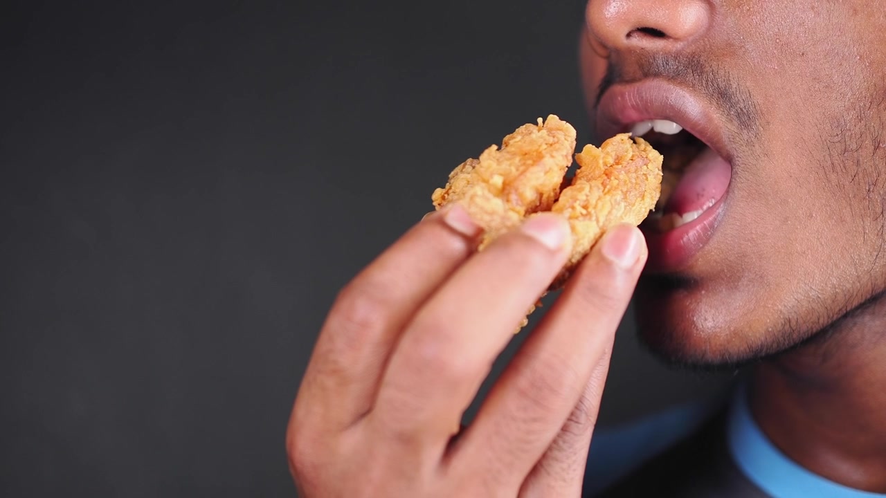 Young Man Eating Crispy Fried Chicken