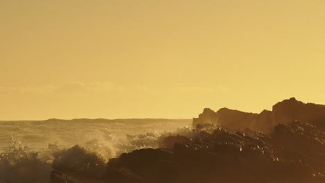 Raue-Meereswellen-Krachen-Auf-Felsen-Und-Erzeugen-Bei-Goldenem-Sonnenuntergang-Eine-Riesige-Gischt---Statische-Aufnahme