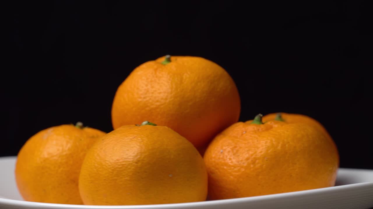 primer plano de mandarinas girando en un tocadiscos en un plato sobre un fondo negro