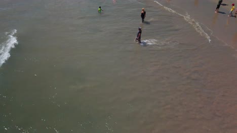 slow tilt up from ocean waves to a crowded beach on a saturday in santa monica, ca