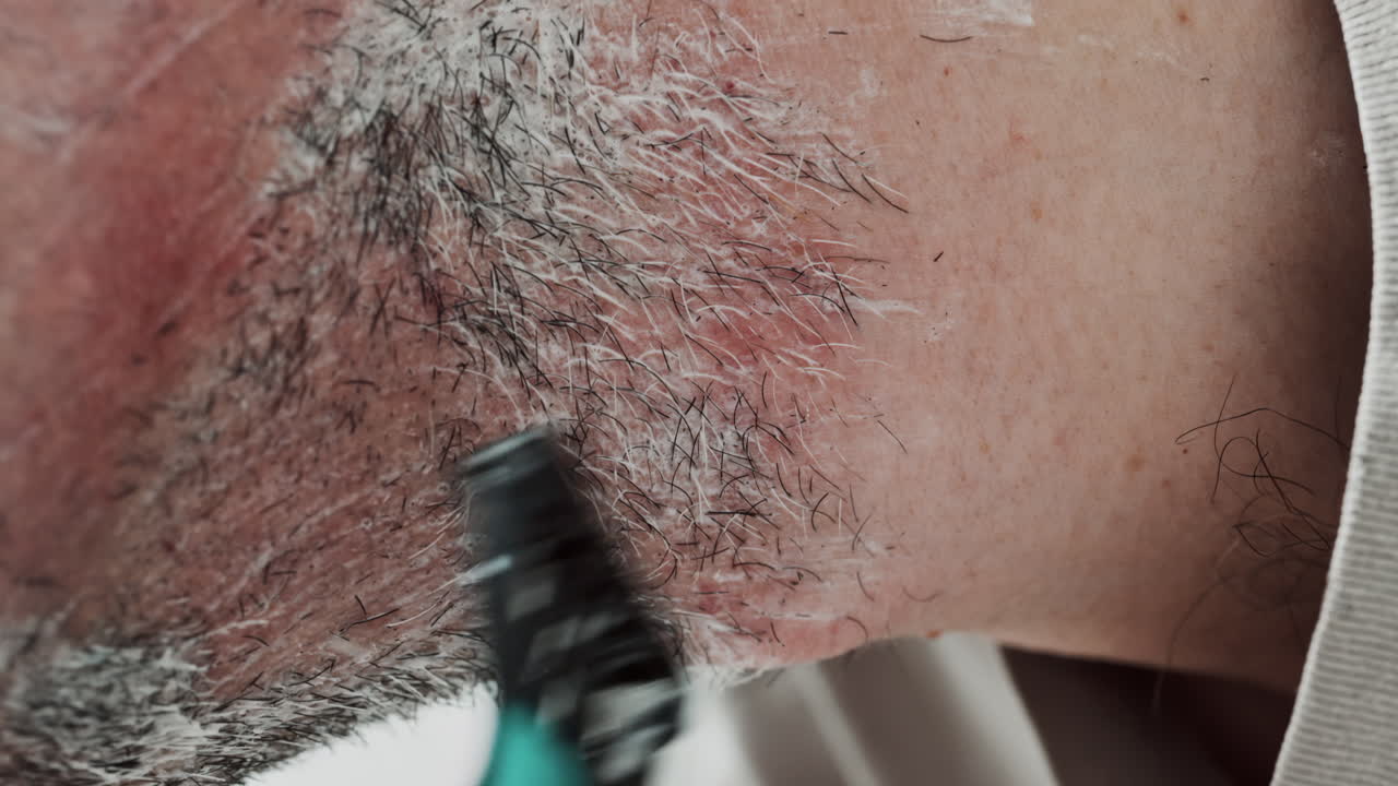 Close up of a man shaving his beard with a razor