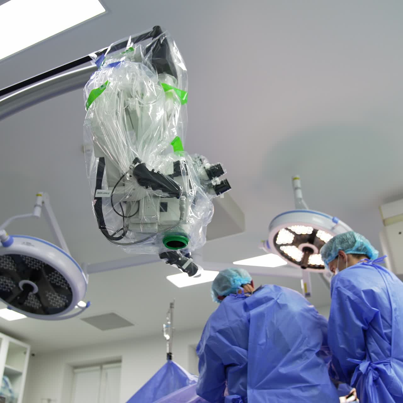 Doctors in blue uniform working in the surgical room. Low angle view at the modern equipment in operational theatre