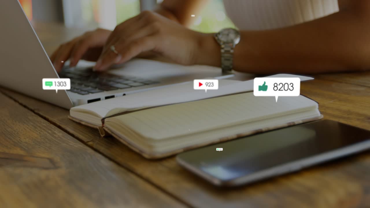 Woman creator typing on laptop while phone sending animated social bubbles showing engagement