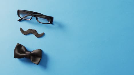 video de bigote falso, gafas negras y pajarita negra sobre fondo azul con espacio para copiar.