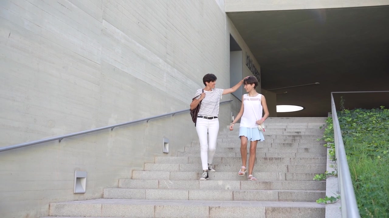 A modern architectural walkway features two individuals gracefully descending a set of stairs