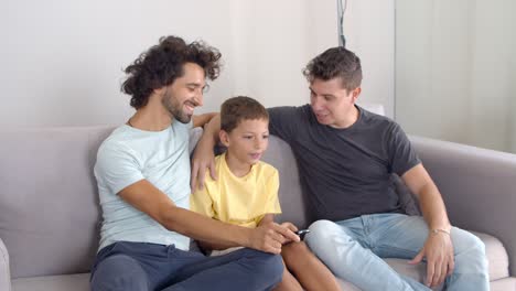 padres homosexuales felices y su hijo sentados juntos