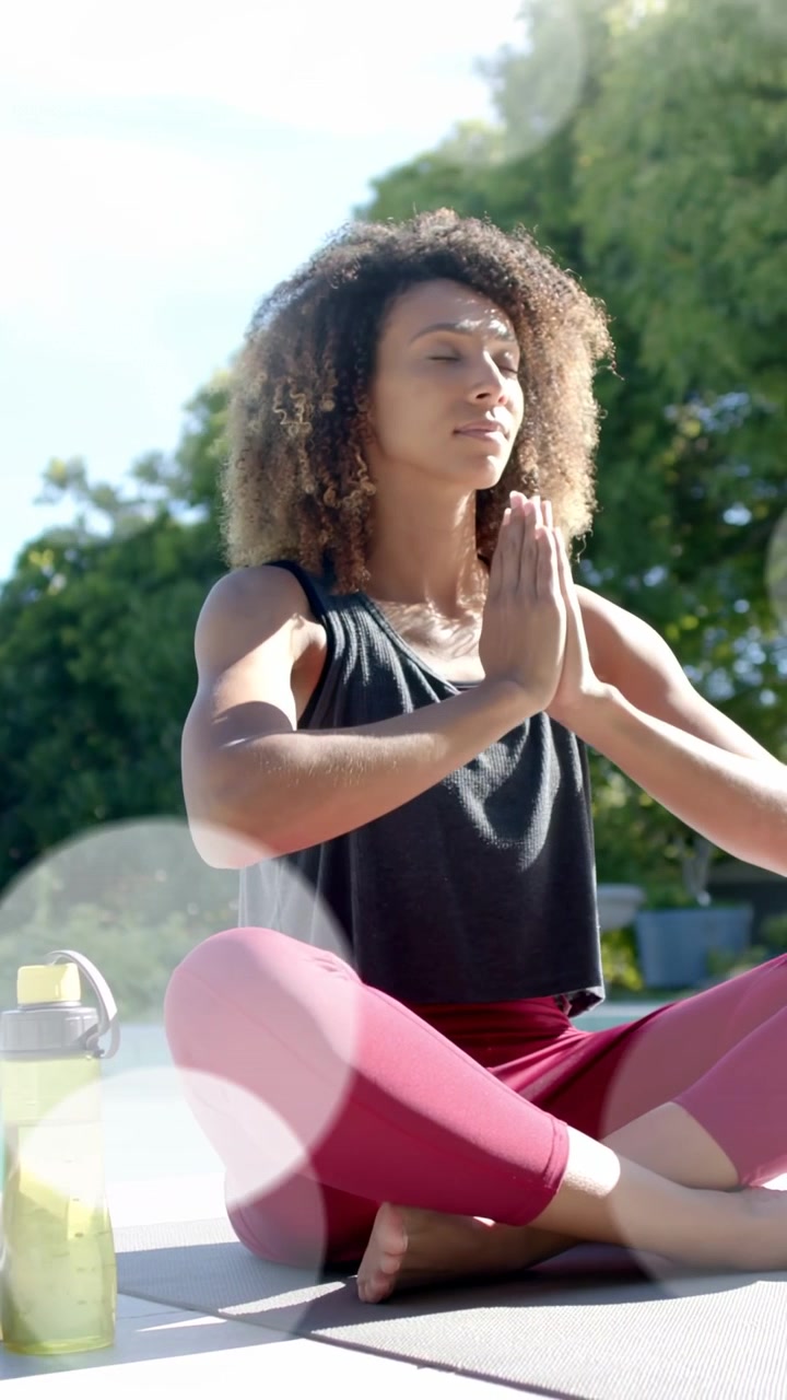 Vídeo vertical: Mulher abaixando as mãos até o peito à beira da piscina com efeito bokeh, posando para a saúde