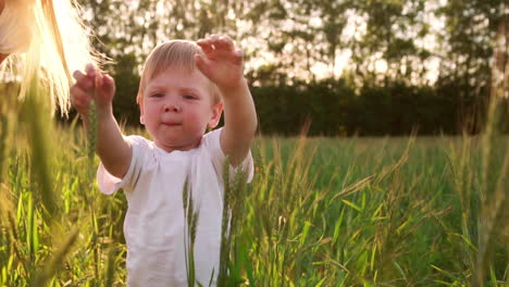 The-concept-of-a-happy-family.-In-the-rye-field,-the-kid-and-his-mother-are-fond-of-smiling-at-each-other-in-spikelets-in-the-backlight