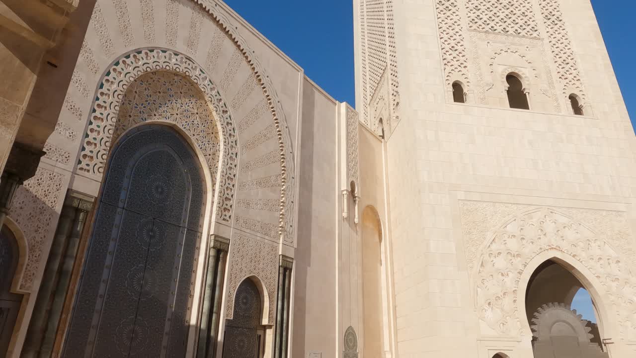 inclinado hacia abajo desde el arco de herradura, revelando el majestuoso minarete de la mezquita de hassan ii en casablanca, marruecos