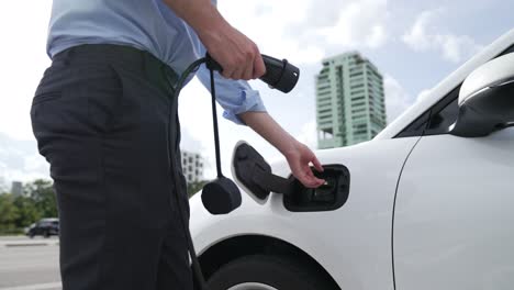 Progressive-businessman-plugs-charger-plug-from-charging-station-to-his-EV.