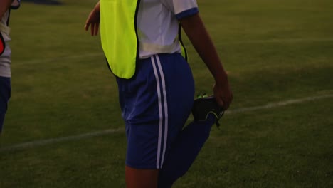 Female-soccer-players-stretching-their-legs-on-soccer-field.-4k