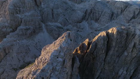 Una-Fascinante-Perspectiva-Aérea-De-Los-Dolomitas,-Con-Picos-Iluminados-Por-El-Sol-Que-Atraviesan-Una-Capa-De-Niebla-Matutina