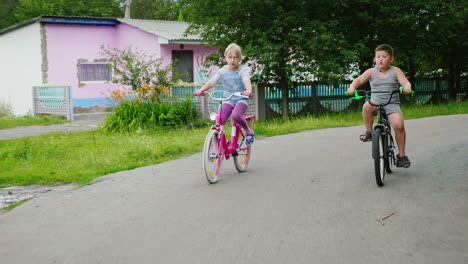 Zwei-Unbeschwerte-Kinder---Ein-Mädchen-Und-Ein-Junge-Fahren-Mit-Dem-Fahrrad-Auf-Der-Straße-1