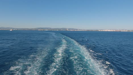 ferry leaving wake in ocean with view of algeciras port in the background