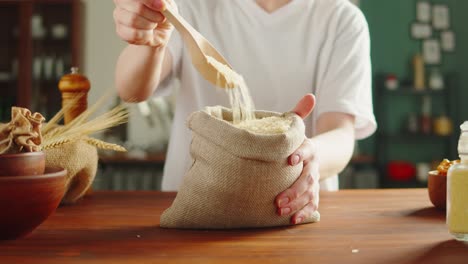 person pouring rice grain into a burlap sack