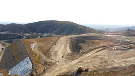 Aerial view of an active landfill with a bulldozer and flocks of birds