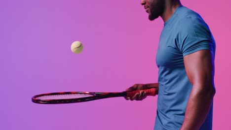 Video-of-midsection-of-african-american-male-tennis-player-bouncing-ball-in-neon-pink-lightning