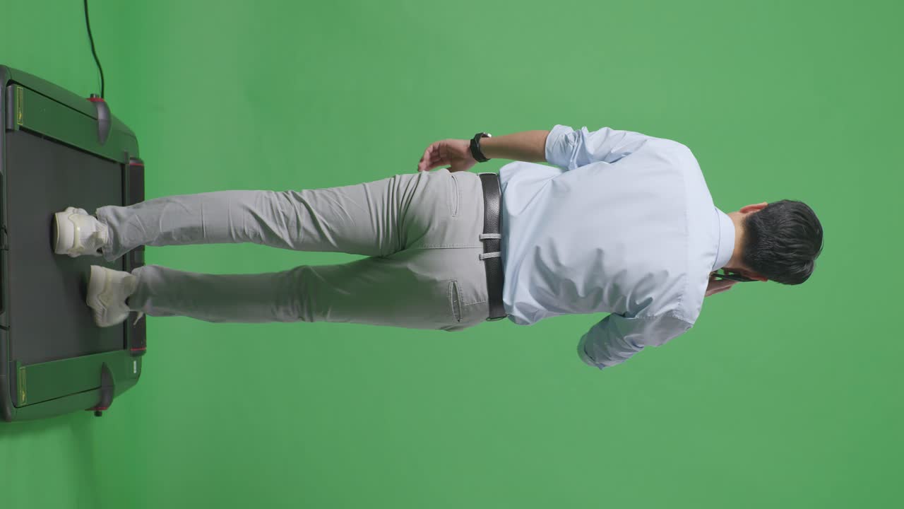 스튜디오에서 녹색 화면 배경에서 는 동안 휴대 전화로 이야기하는 아시아 사업가의 전체 몸의 뒷면