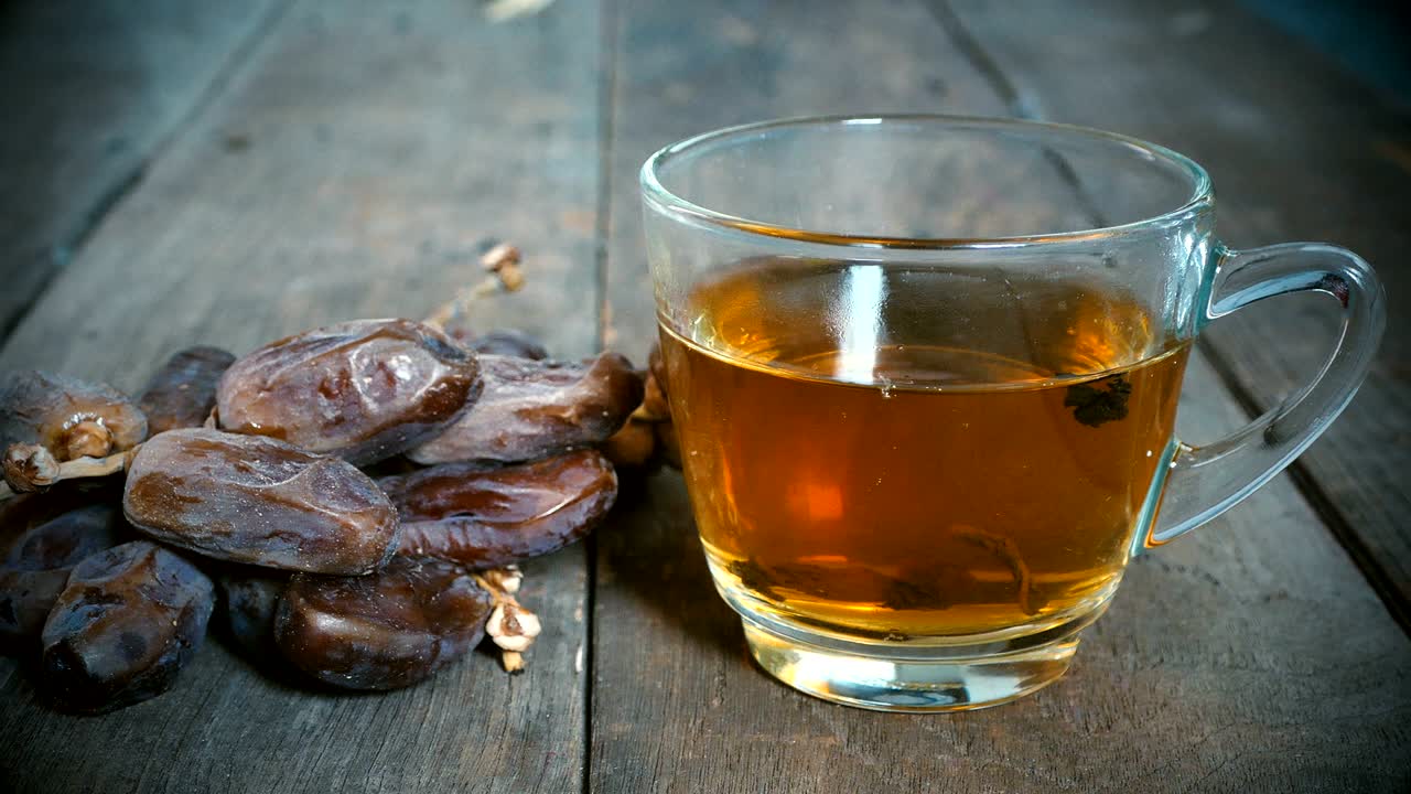 4K, close up dolly, palm dates fruit with cup of tea on old wood table