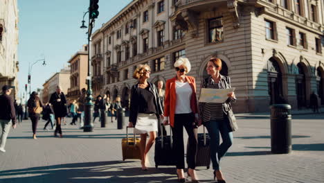 three women travelers walking with luggage on a city street