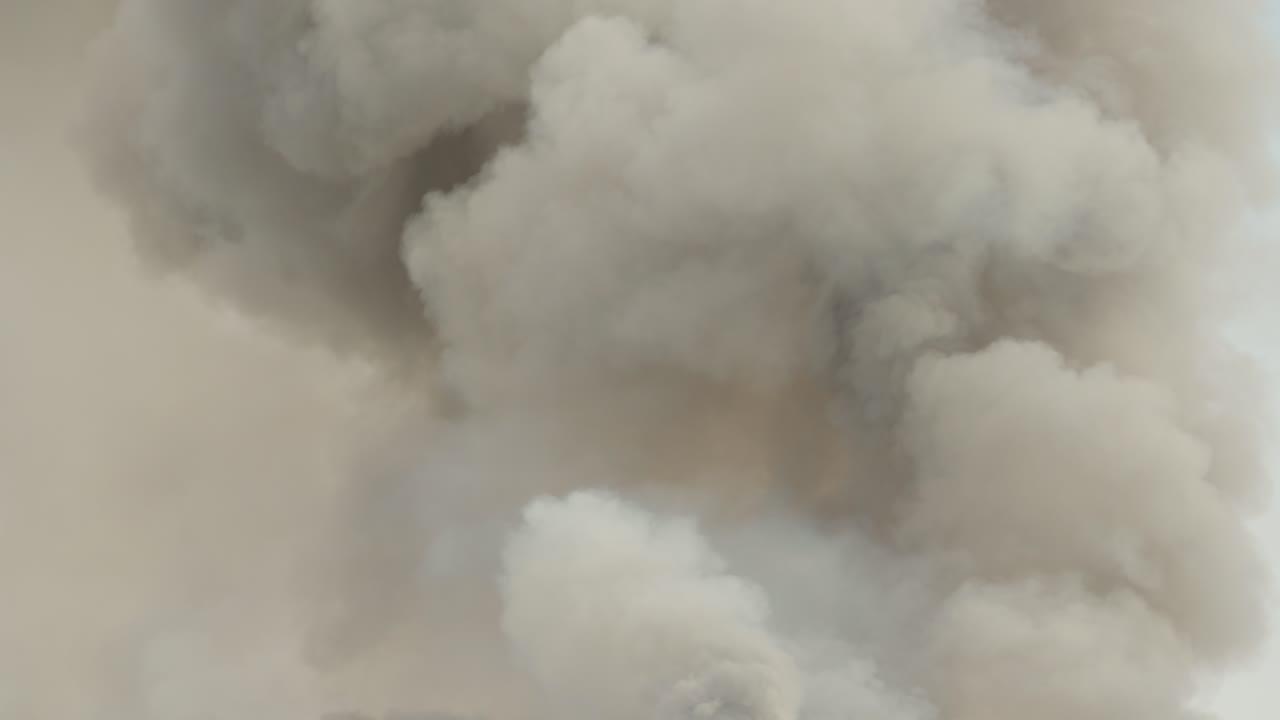 Black smoke clouds and flames rise into the sky.