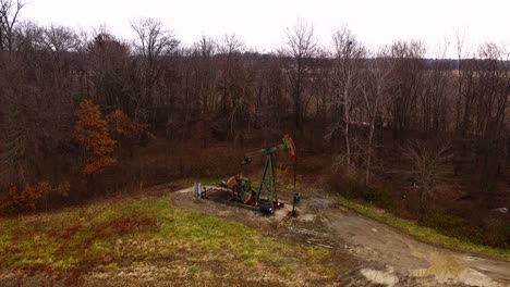 An-overhead-view-of-a-functioning-pump-jack-with-winter-trees-in-the-background