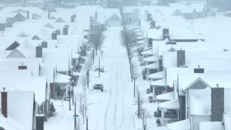 suburban street blanketed in snow, with distinct tire tracks and houses in a row