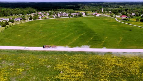 Skujene,-Latvia,-Europe---A-Truck-and-a-Car-Driving-Along-the-Rural-Highway---Aerial-Drone-Shot