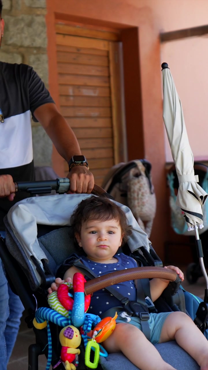 Padre che spinge il bambino nel passeggino all'aperto
