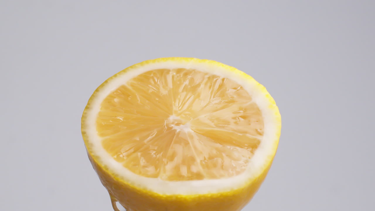 tiro macro de cámara lenta de agua que fluye de la rodaja de limón sobre fondo blanco