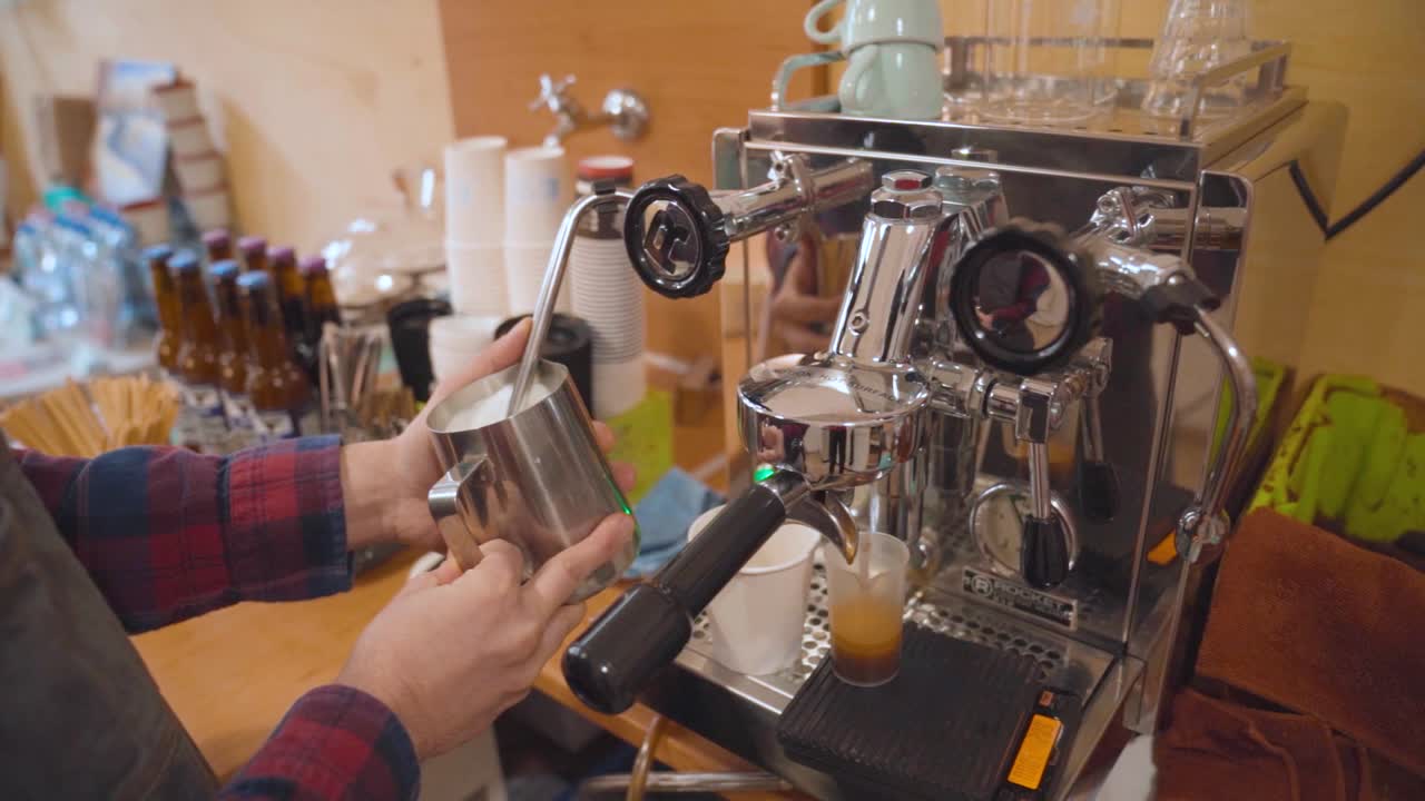 Barista steaming milk in stainless steal jug