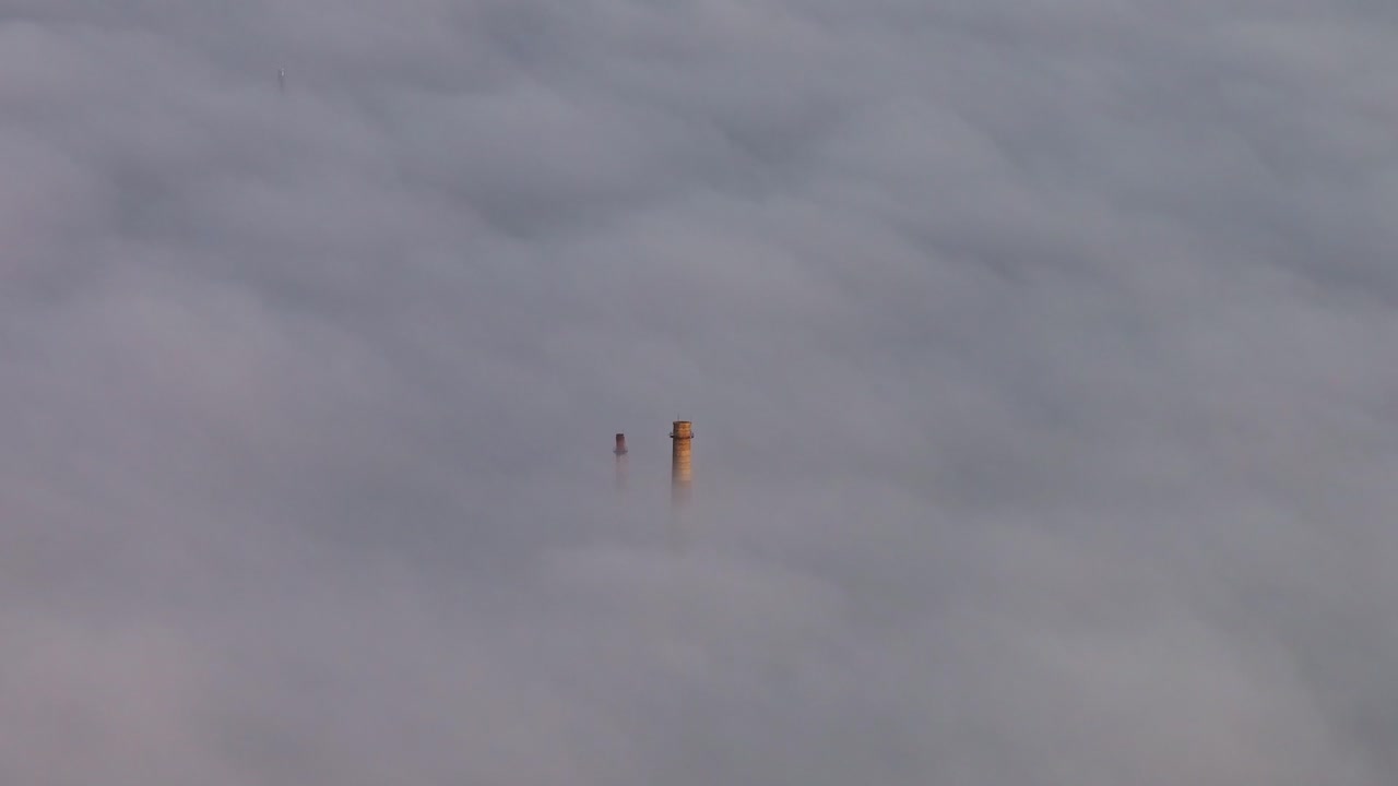 Chimney tops pierce thick morning fog as golden light softly glows at sunrise