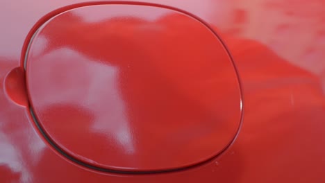 close-up of a hand plugging in an electric vehicle charger, red car, daytime