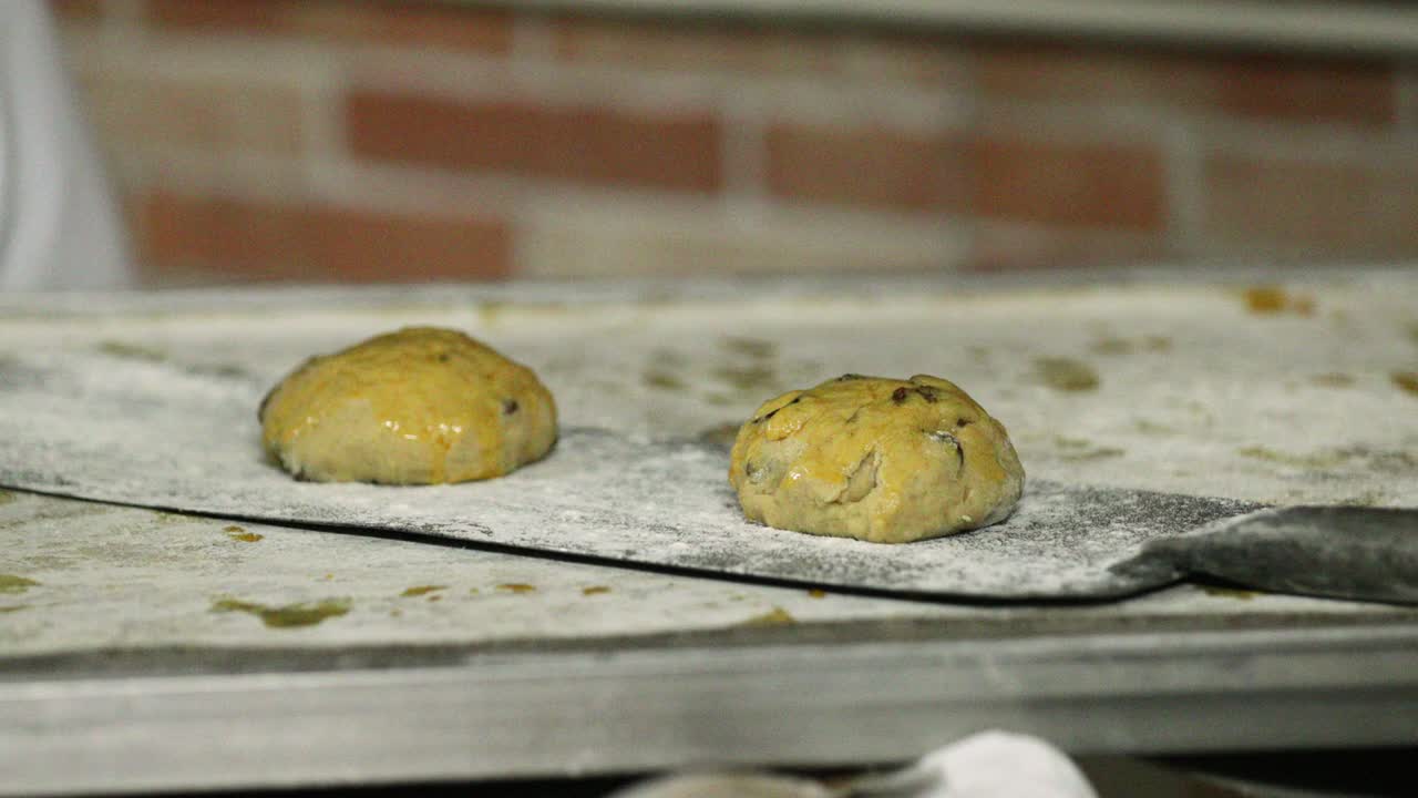 colocando la masa de galletas de pasas en una cáscara de horneado en la cocina de la panadería