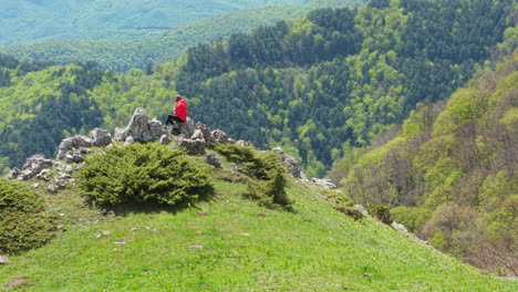 aerial view of a lone woman hiker gazing into the vast green wilderness from an elevated spot. a peaceful outdoor escape in the heart of bulgaria’s scenic mountains.