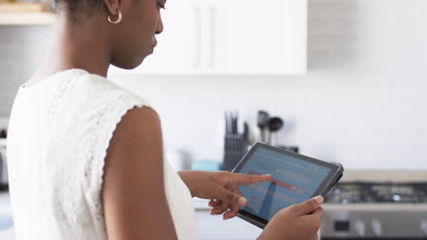 A-young-African-American-woman-is-examining-smart-home-app-energy-usage-on-a-tablet