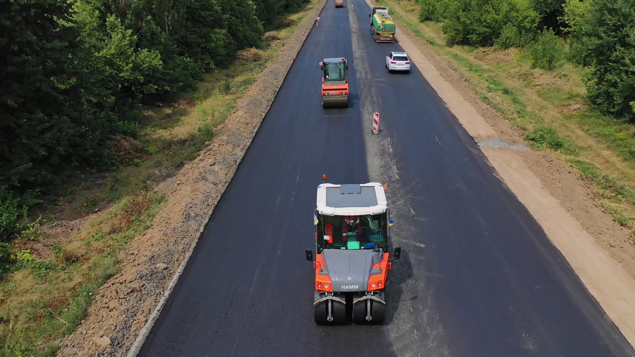 Repairing with vibration roller. Aerial view of the new asphalt road under construction