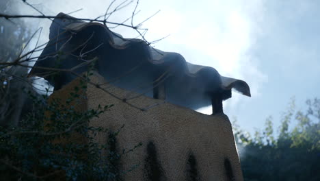 smokes rising from an old barbecue chimney with sunlight behind