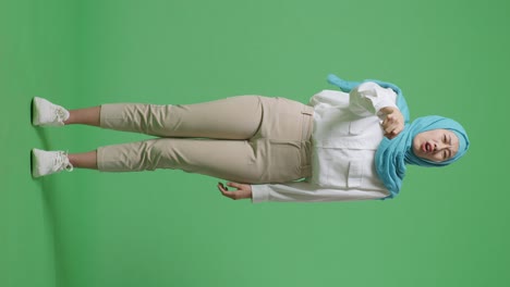 full body of asian muslim woman shouting at camera while standing in the green screen background studio