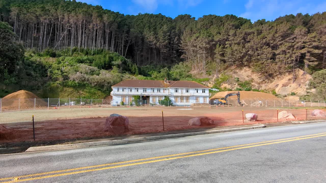 Old Building Undergoing Renovation at a Construction Site with Forested Hills