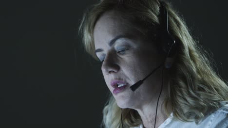 mujer de negocios con auriculares trabajando en una oficina oscura