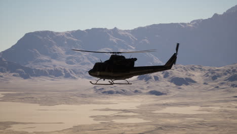 military helicopter flying over mountainous desert landscape