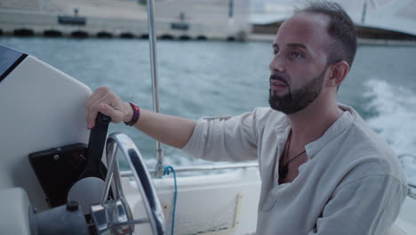 bearded man driving a boat on the water