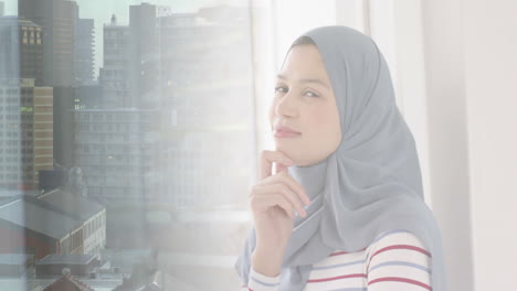 animation of cityscape over biracial woman in hijab smiling