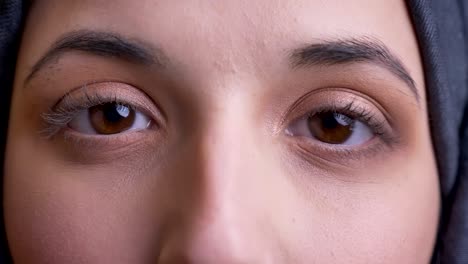 retrato macro en primer plano de una joven y hermosa mujer árabe de ojo marrón parpadeando mientras mira directamente a la cámara con expresión facial neutral