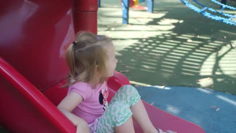 Slow-motion-of-a-4-year-old-girl-on-a-slide-smiling-happily